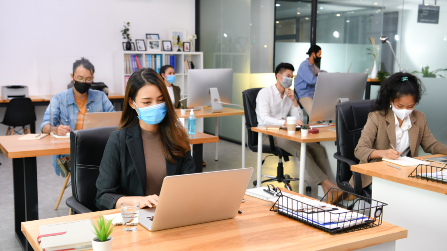 Asian office workers wearing face masks working in the new normal office and doing social distancing during coronavirus covid-19 pandemic